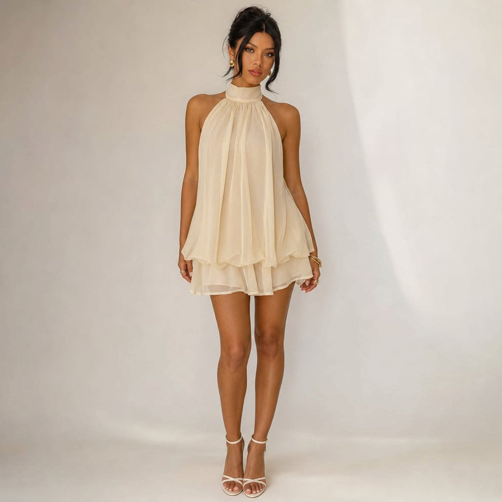 Beige chiffon mini dress with gathered halter neckline, open back and two-tier ruffle hem, front view on white background