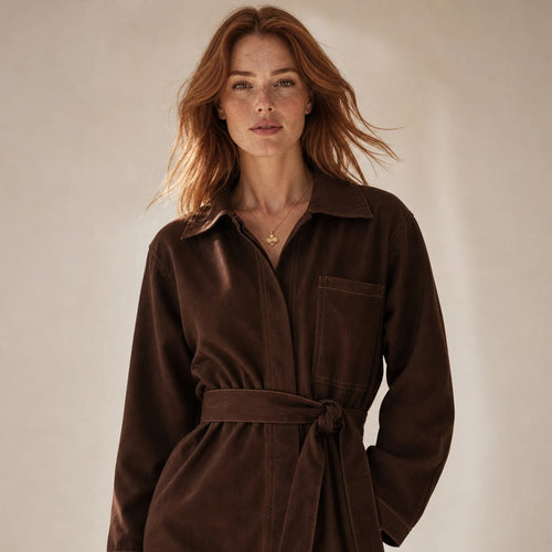 Model wearing Amy chocolate denim longline top with waist tie cinched, styled with wide-leg trousers