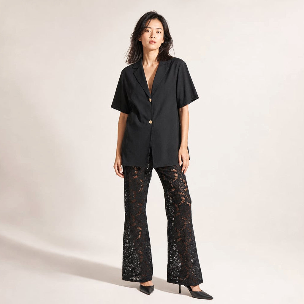 Model wearing the Jordan black set, 172 cm frame in size S, showing the relaxed wide leg and fitted cotton top with V-neckline and gold button detail.