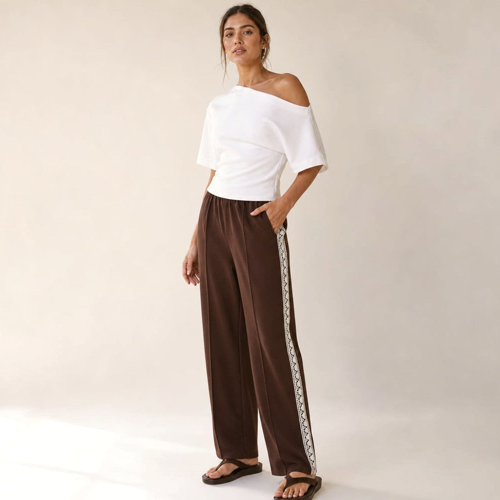 Straight-leg chocolate trackpants with continuous side stripe and lace hem detail, styled on model