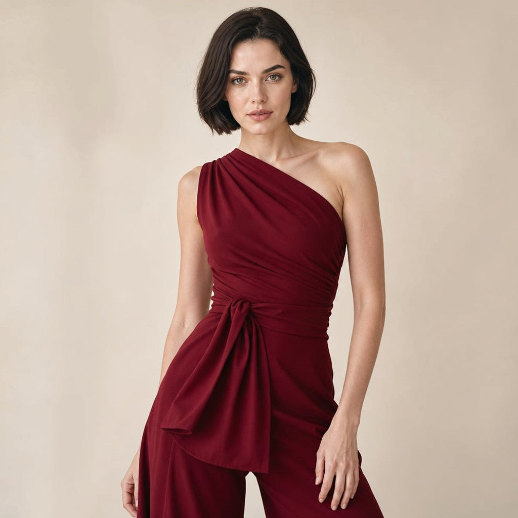 Model wearing Slaestel burgundy one-shoulder wide-leg jumpsuit with self-tie waist, full-length editorial shot