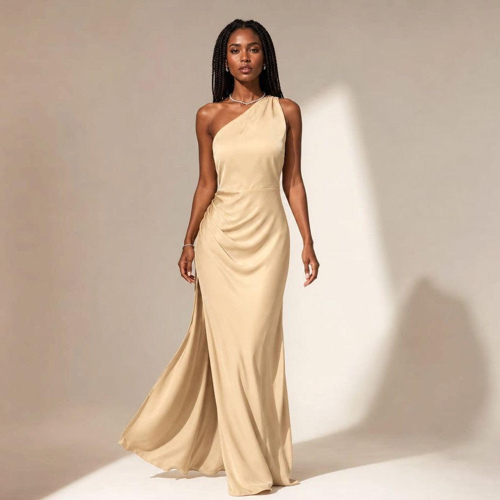 Model wearing a light brown asymmetrical maxi dress with one side sweeping the floor and a raised slit hem on the opposite side.