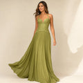 Model wearing the Aelva green corset maxi dress, showing the structured boned bodice and fluid pleated floor-length skirt
