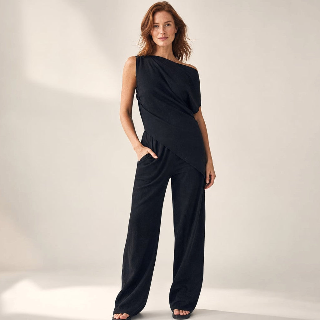 Model wearing Parkel black cotton co-ord set with asymmetric off-the-shoulder top and wide-leg trousers, full-length editorial shot