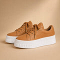 Side profile of tan chunky platform lace-up sneakers showing the full stacked sole height and lace-up front detail