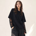 Model wearing Francesca black cotton-blend knit top with lace forearm sleeves, styled with tailored trousers