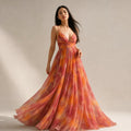Model wearing Kraendov orange abstract-print maxi dress, showing fitted bodice and flowy skirt in motion